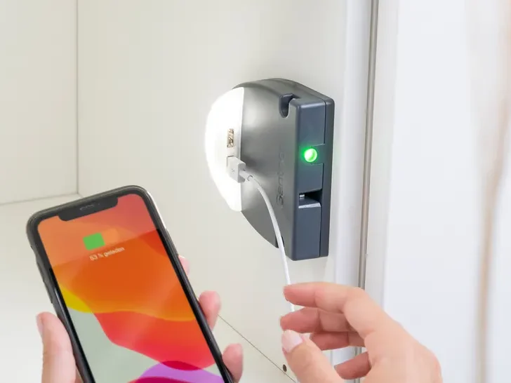 Smartphone wird mit einem kabelgebundenen Ladegerät am Spindschloss verbunden, LED-Anzeige leuchtet grün.