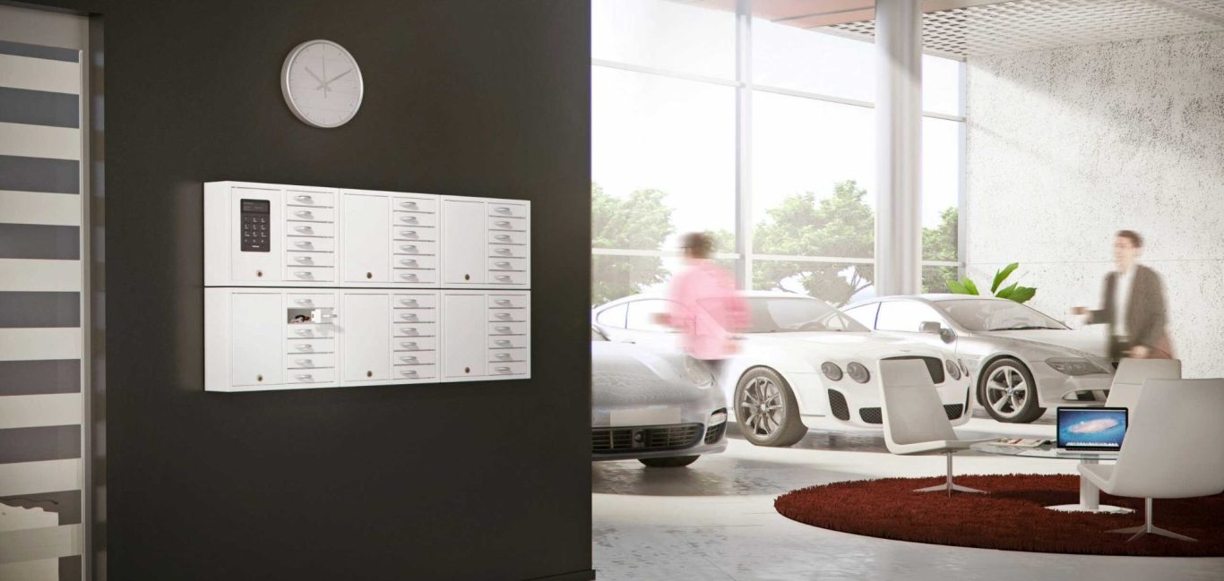 Moderne Empfangshalle mit CREONE Schlüsselschränken und zwei Personen neben Luxusautos.