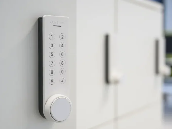 Modernes digitales Schrankschloss mit Ziffernblock und Drehknopf, montiert an einem weißen Schrank.